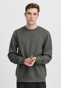 Dunkelgrüner Sweatshirt aus weichem Stoff, mit Rundhalsausschnitt und langen Ärmeln. Das Design umfasst gerippte Bündchen und Saum.