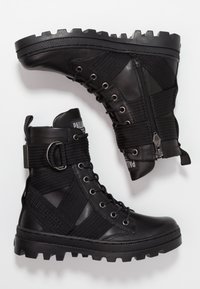 Černé kožené bojové boty s tlustou gumovou podrážkou, bočním zipem, šněrováním a elastickým páskem s kovovou sponou, zobrazené z bočního a spodního pohledu.