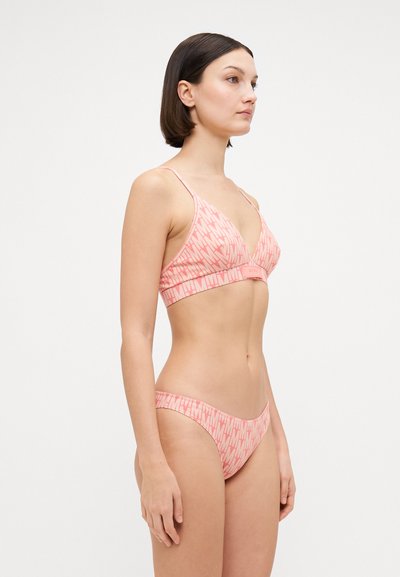 Rózsaszín bikiniszett, amely háromszög alakú bralette-ből és hozzá illő, alacsony derekú bugyiból áll, mindkettő ismétlődő grafikai mintával és vékony pántokkal.
