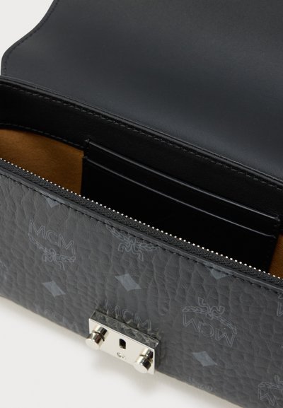 Μαύρο δερμάτινο τσάντα σχεδιαστή με υφή και ασημένιο κούμπωμα, ανοιχτή για να δείχνει εσωτερικές θήκες για κάρτες και φερμουάρ σε διαμέρισμα.