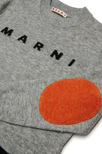 Pilkas megztinis su juodais "MARNI" užrašais ir oranžiniu apvaliu pleistru ant alkūnės. Megztas audinys, su raukinėta apykakle ir rankogaliais.