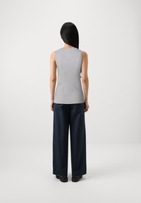 Gray sleeveless top with a round neckline, paired with loose-fitting navy pants and black footwear. Focus on clean lines and classic colors.