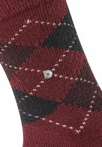 Skarpetka w czerwono-czarny wzór argyle z teksturowanym splotem, z kremowymi akcentami i okrągłą metką marki z boku.