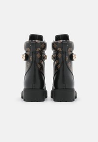 Bottes noires montant à la cheville avec motif doré, boucles réglables, finition texturée et semelles en caoutchouc épaisses. Matière lisse et design arrondi.