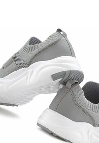 Sneakers grigi con tomaia in maglia e accenti testurizzati, suola bianca e linguetta per un facile indossamento.