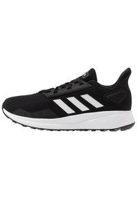 Czarne buty sportowe z białymi akcentami, siateczkowa cholewka oraz teksturowane wykończenia. Posiadają sznurowadła, cushioned sole oraz konturowane wsparcie pięty.