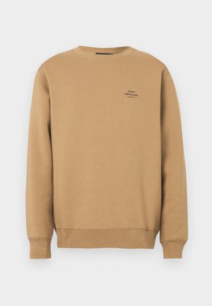 Beige genser med rund hals og ribbestrikkede mansjetter og nederkant, med en liten svart "Mads Nørgaard København"-logo på venstre side av brystet.