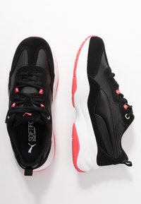 Černé a růžové tenisky Puma s bílými podrážkami, polstrovanými límci a měkkými komfortními vložkami, zobrazené z horního a bočního pohledu na bílém pozadí.