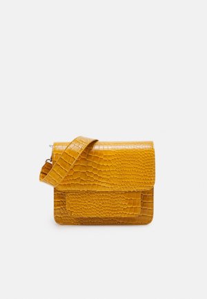 Sennepsgul taske med tekstureret krokodillemønster og bred justerbar rem på hvid baggrund.