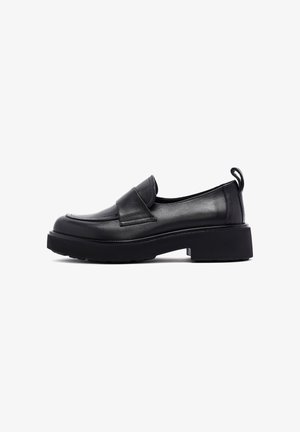 Mocassins en cuir noir avec un bout arrondi, un petit talon carré et un rabat décoratif. Comprend une languette à l'arrière et une semelle texturée.
