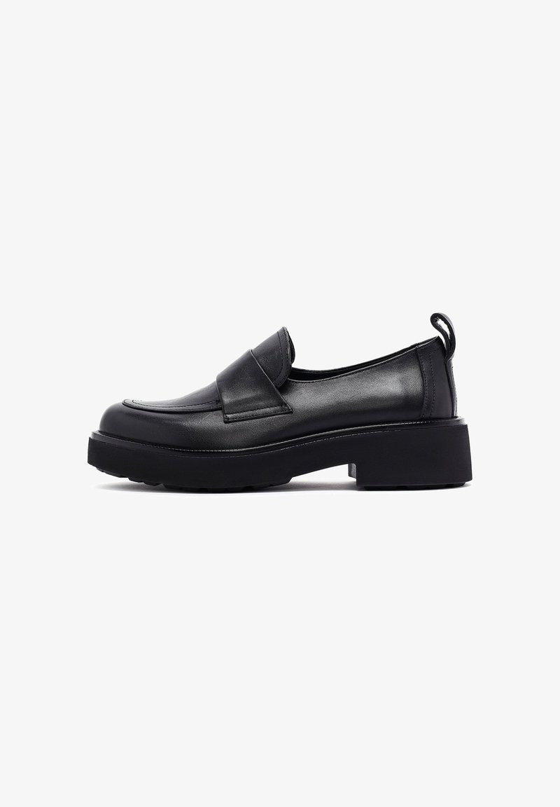 Mocassins en cuir noir avec un bout arrondi, un petit talon carré et un rabat décoratif. Comprend une languette à l'arrière et une semelle texturée.
