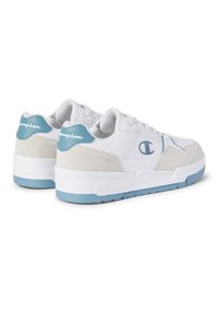 Weiße Sneaker mit glattem Lederobermaterial, Wildlederakzenten und einer hellblauen Gummisohle. Logo auf der Ferse aufgestickt. Klassisches Low-Top-Design.