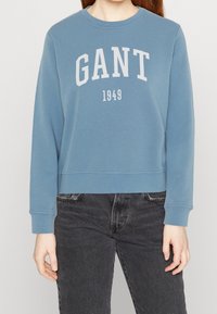 Felpa in cotone blu con colletto a girocollo, caratterizzata dalla scritta "GANT" e "1949" stampata in bianco sul petto. Fit rilassato e polsini a coste.