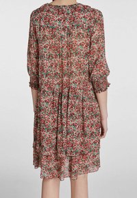 Robe florale en tissu léger et semi-transparent, présentant un motif de fleurs rouges et vertes, des manches volantées et un design de jupe à volants.