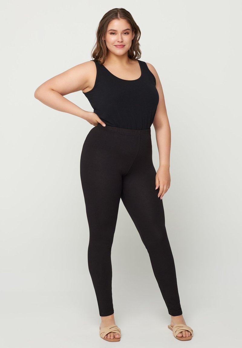 Débardeur noir associé à des leggings noirs. Le débardeur a une encolure ronde et les leggings présentent une taille sans couture et une coupe ajustée.