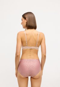 Lys rosa bh med tynde stropper og hægteåbning, parret med højtaljede trusser i et tekstureret pink mønster. Glat stof, minimal detaljer.