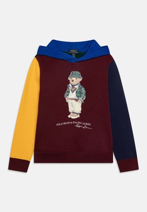 Børns hættetrøje med vinrød krop, gul venstre ærme, navy højre ærme, blå hætte og en Polo Bear-grafik i afslappet outfit foran i midten.
