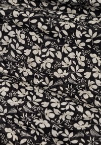 Čierna tkanina s bielym kvetinovým vzorom, obsahujúca rôzne tvary listov a malé kvety. Mäkká textura, ľahký materiál.