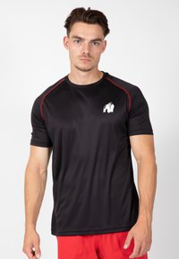Zwarte sport T-shirt met rode schouderaccenten en een wit gorillalog op de linkerborst. Heeft korte mouwen en een gladde textuur.