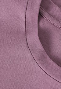 Light purple cotton t-shirt featuring a round neck and smooth texture. Close-up view highlights the even stitching and fabric quality.