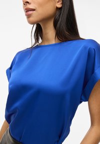Blusa in satin blu con una vestibilità ampia, maniche corte e scollatura rotonda. Texture liscia con una finitura lucida.