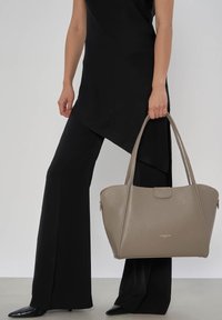 Grijze leren handtas met een gestructureerd ontwerp, twee verlengde handgrepen en een subtiele getextureerde afwerking. Gouden logo aan de voorkant.