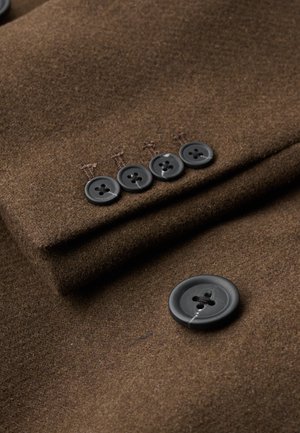 Tela de lana marrón con una textura suave, que presenta cinco botones negros y un sutil detalle de costura.