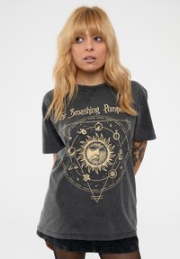 Dark gray, oversized t-shirt featuring a gold graphic of the sun, a face, and zodiac symbols. Soft, cotton material with short sleeves.