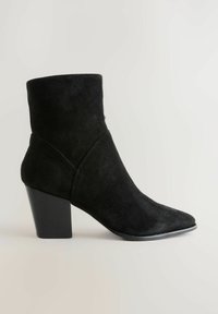 Crne suède čizme do gležnja s oštrim vrhom, koje imaju sužen blok petu i glatku teksturu. Dizajn je elegantan s minimalnim naglascima.