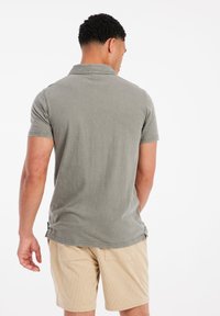 Grijze poloshirt met korte mouwen en een zachte textuur, gedragen met beige corduroy shorts met een verticale streeppatroon.