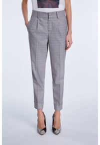 Pantalons à carreaux gris avec des plis, design fuselé et ourlets roulés. Portés avec des escarpins noirs dotés d'un cap toe texturé.