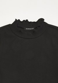 Svart ribbad polotröja med en volangkrage och en tagg med "even&odd" varumärkesnamn. Mjuk textur och åtsittande design.