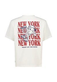 Valkoinen puuvillati-paita, jossa on graafinen printti sarjakuvamaisesta koripalloilijasta, punainen teksti "NEW YORK" ja sininen teksti "HEART OF THE GAME".