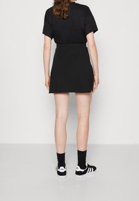 Černý krátký rukávový top v kombinaci s černou mini sukní. Doplněno černobílými teniskami se třemi pruhy a ponožkami po kotníky.