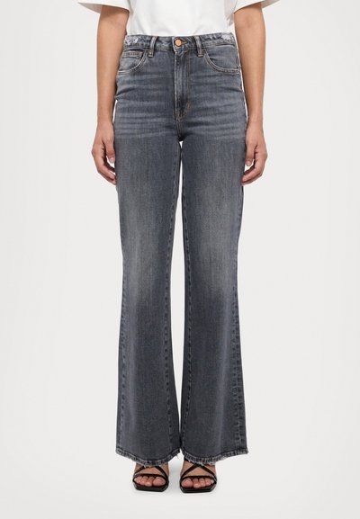 Jeans cu talie înaltă, evazați, din denimul gri închis, având închidere cu nasture, cinci buzunare și tiv brut. Modelul poartă sandale negre cu curea.