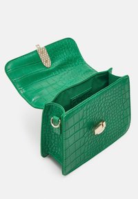 Borsa in pelle verde con motivo coccodrillo, dalla texture liscia, con chiusura in metallo dorato e un ampio interno. Design con pattina aperta per un facile accesso.