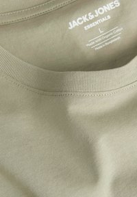 Olivegrünes T-Shirt mit Rundhalsausschnitt aus Bio-Baumwolle. Hat eine glatte Oberfläche und ein Etikett mit Marken- und Materialdetails.