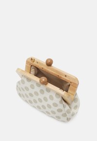 Small beige fabric clutch with large polka dots, wooden frame, and round brown clasp, shown open against a white background.