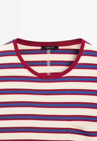 Pyöreäkaltainen raitapaita, jossa on punaisia, sinisiä ja kermanvärisiä vaakaviivoja sekä pieni oikean alakulman tasku, jossa lukee Massimo Dutti.