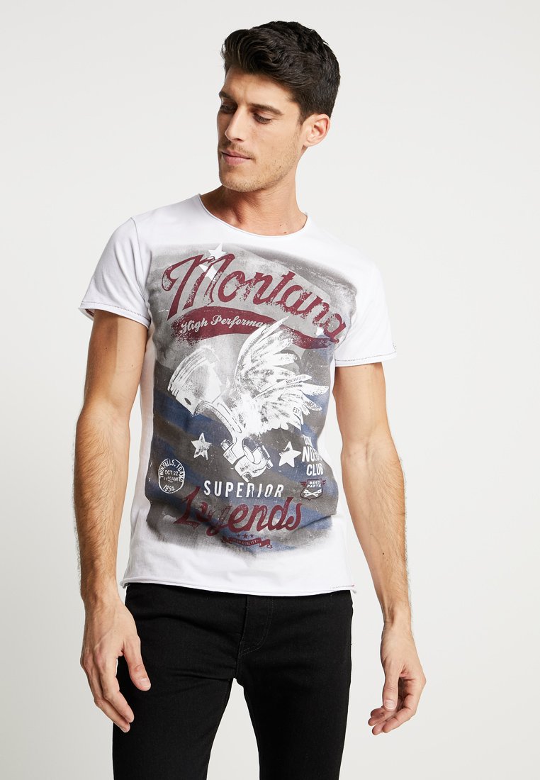 Camiseta de algodón blanca con un estampado gráfico de un águila, estrellas y texto en tonos rojos y azules. Mangas cortas y un escote redondo.