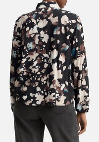 Blusa de manga larga en negro con un estampado floral que presenta acentos en beige, marrón y verde azulado. Hecha de una tela suave con un diseño de cuello.
