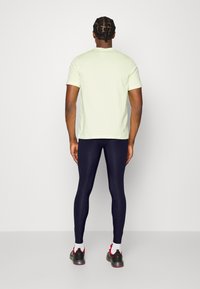 Ljusgrön kortärmad t-shirt i kombination med marinblå leggings. T-shirten har rund hals; leggingsen är figurnära och släta.