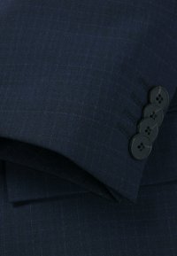 Navy blazer cuff featuring a woven texture, four black buttons for closure, and slight tonal patterns adding subtle detail.