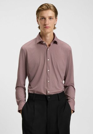 Bordeauxfarbenes, gemustertes Hemd mit spitzem Kragen und langen Ärmeln, kombiniert mit schwarzen Hosen, die eine glatte Stoffoberfläche aufweisen.