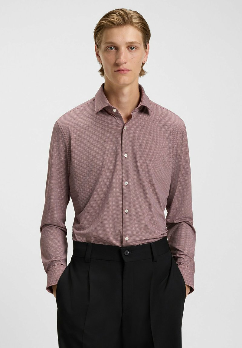 Bordeauxfarbenes, gemustertes Hemd mit spitzem Kragen und langen Ärmeln, kombiniert mit schwarzen Hosen, die eine glatte Stoffoberfläche aufweisen.