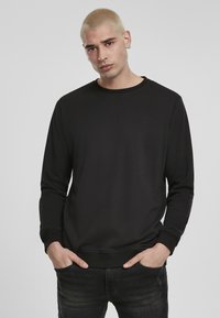 Svart hettegenser laget av glatt stoff, med rund hals og lange ermer. Ribbede mansjetter og hem-detalj. Enkel design uten mønster.
