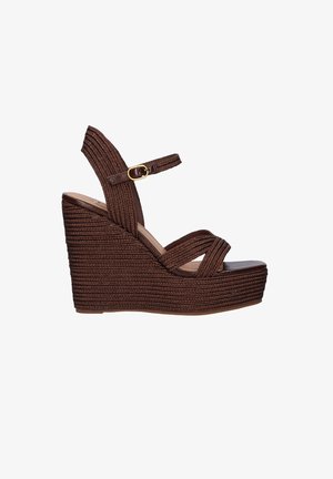 Sandalia cuña marrón tejida con correa en el tobillo y hebilla dorada, con tacón de plataforma alto y diseño de punta abierta.