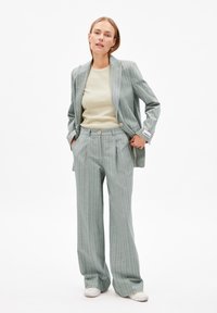 Lichtgroen geruit pak met een getailleerde blazer en wijde broekspijpen. De stof heeft een gladde textuur en de blazer is voorzien van twee knopen.