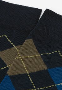 Mørkeblå strømper med et geometrisk argyle-mønster i brunt, grønt og blåt. Struktureret strikstof og ribbede manchetter.