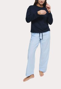 Marinblå långärmad topp med rundad halsringning, tillsammans med ljusblå, löst sittande pyjamasbyxor med dragsko i midjan.